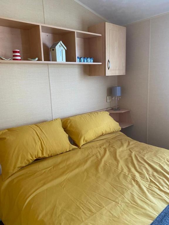 uma cama grande com lençóis amarelos num quarto em Comfy 2 bed holiday caravan em Whitstable