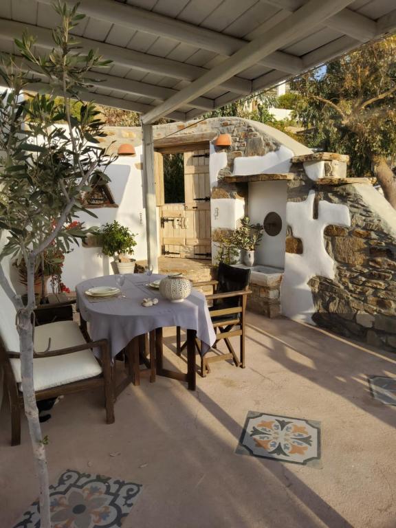 un patio con mesa, sillas y horno de piedra. en Romantic sunset cycladic house in Sotires en Episkopianá