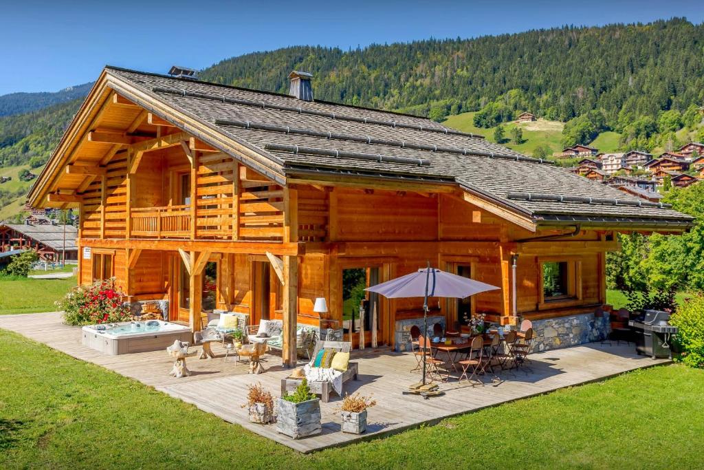 a large log cabin with a table and chairs at Chalet Ibusta - OVO Network in Le Grand-Bornand