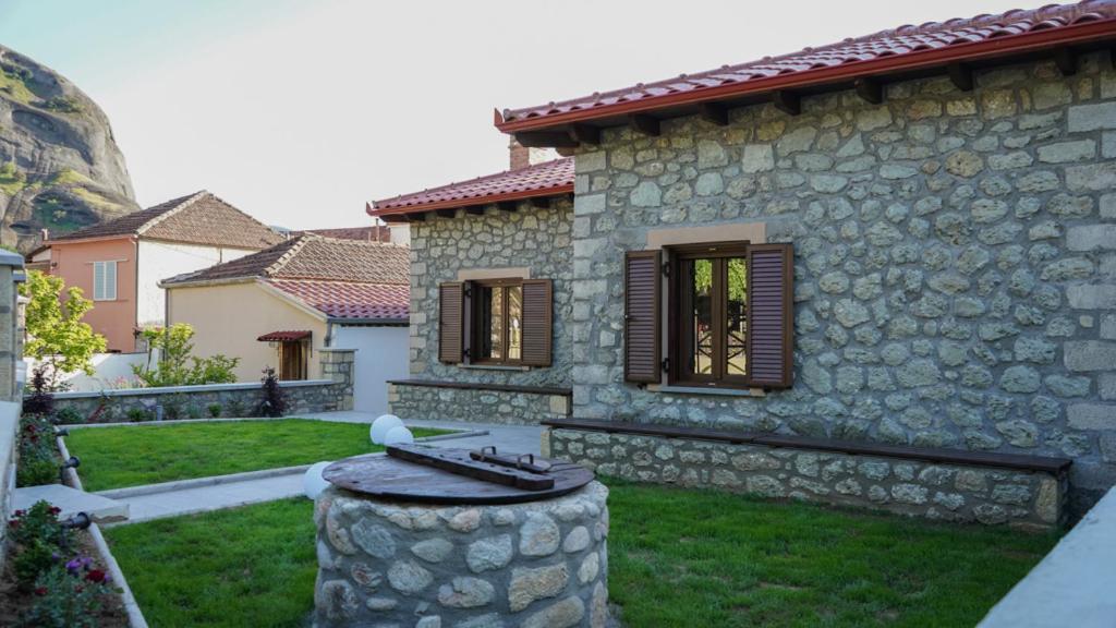 uma casa de pedra com uma parede de pedra e um quintal em Guesthouse Pyxari em Kalabaka