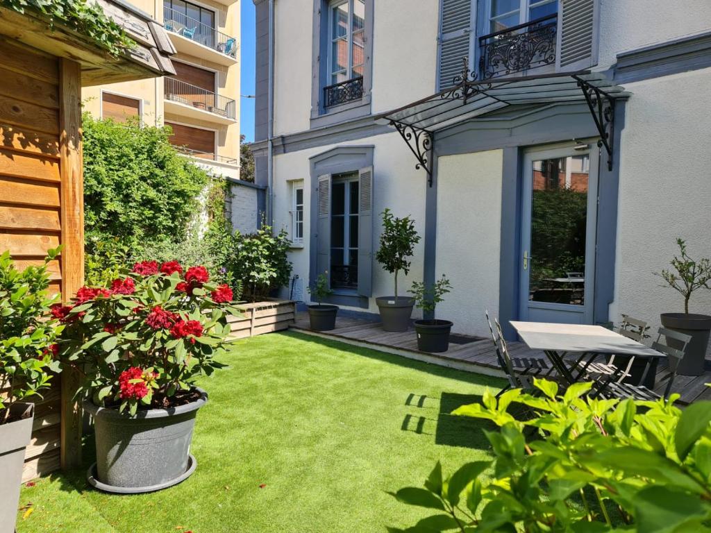 um pequeno jardim com flores vermelhas e uma mesa em La Maison V.H., Appartements d'Hôtes em Troyes