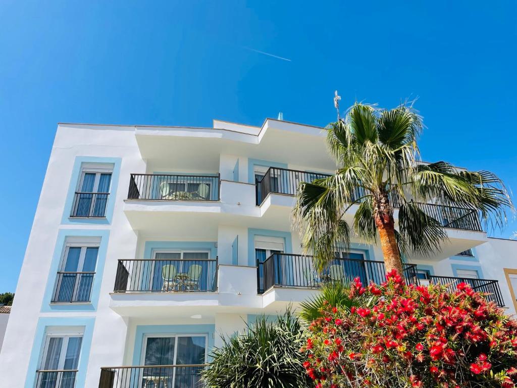 ein weißes Gebäude mit einer Palme davor in der Unterkunft Blue House Mallorca in Ses Salines