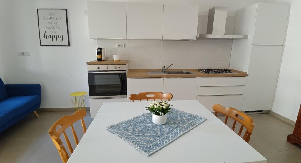 une cuisine avec une table et des chaises blanches et une cuisine avec un canapé bleu dans l'établissement SUN LIGHT, à Tortolì