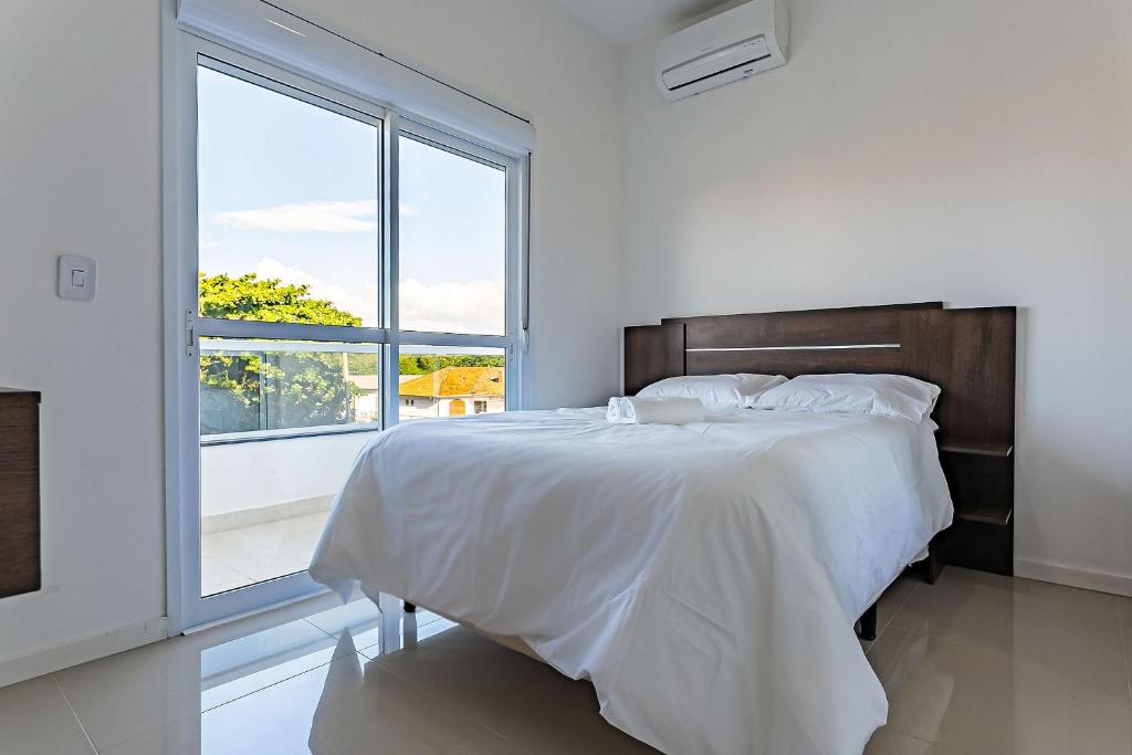 um quarto com uma cama e uma grande janela em Apto amplo com suíte na praia do Santinho SBR304 em Florianópolis