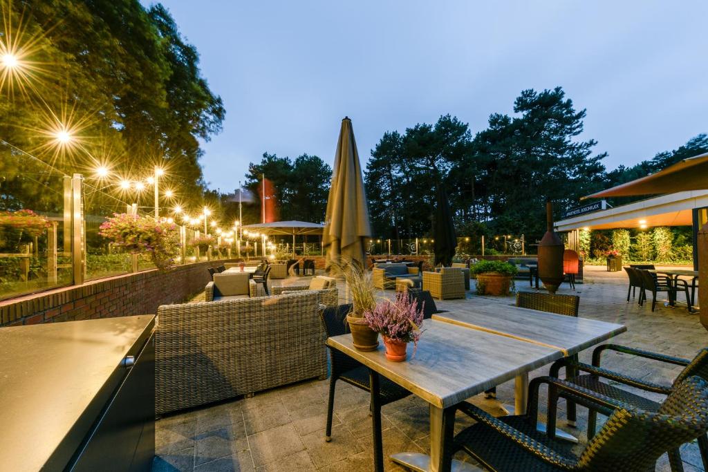 a patio with a wooden table and chairs and lights at WestCord ApartHotel Boschrijck in West-Terschelling