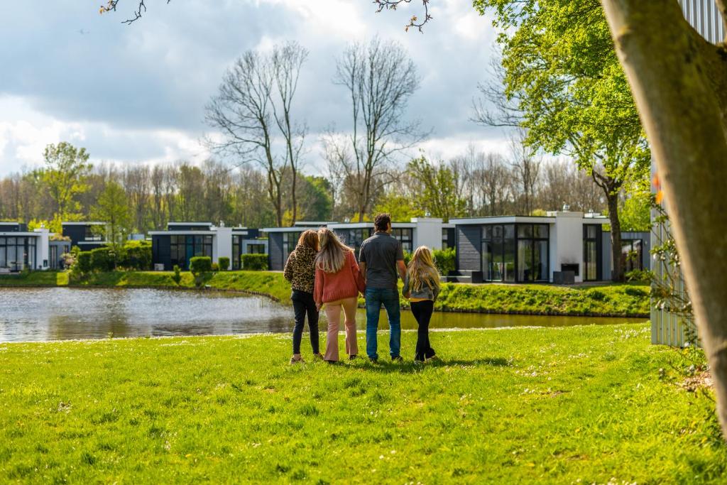 a group of people standing in the grass near a lake at EuroParcs Spaarnwoude in Halfweg