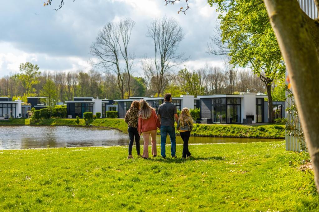 eine Gruppe von Menschen, die im Gras in der Nähe eines Sees stehen in der Unterkunft EuroParcs Spaarnwoude in Halfweg