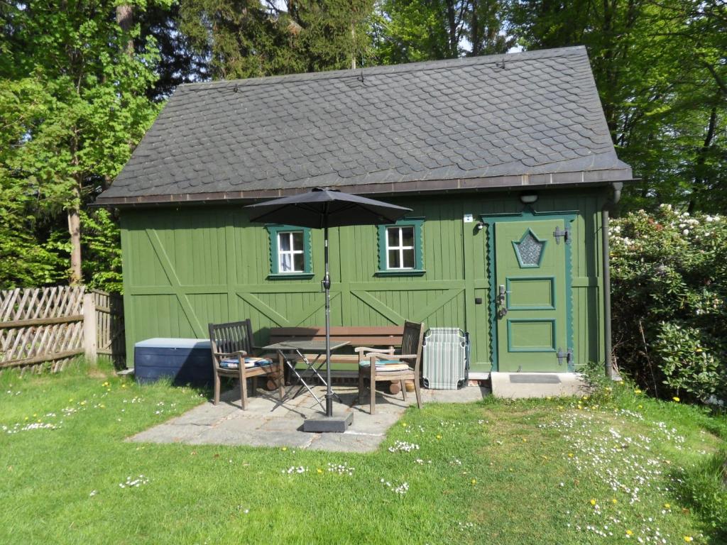 einem grünen Schuppen mit einem Tisch und einem Regenschirm in der Unterkunft Tiny House in Thermalbad Wiesenbad