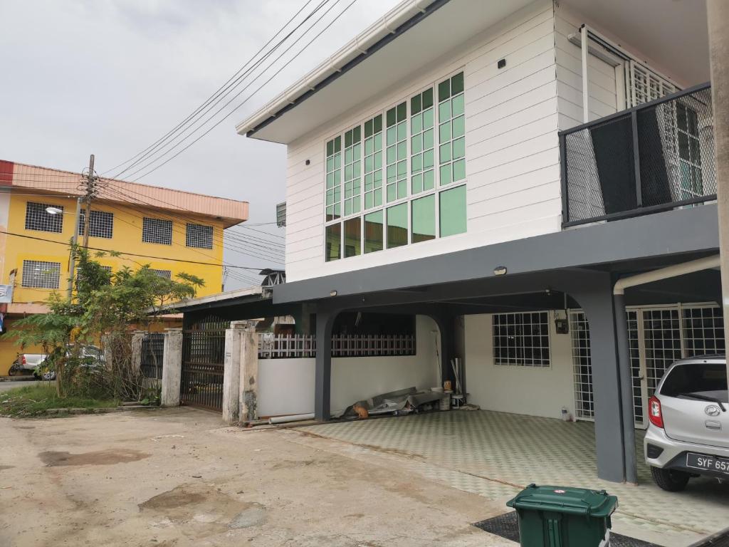 uma casa branca com um carro estacionado em frente dela em NJ_Homestay@KKIA/Petagas KK em Kota Kinabalu