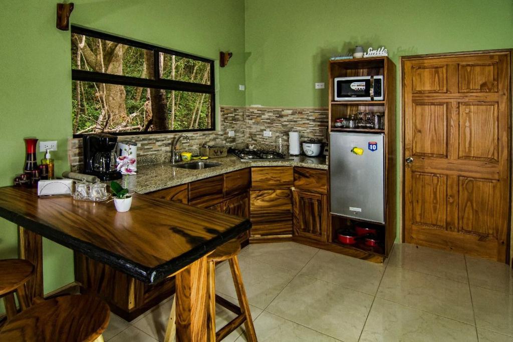 a kitchen with green walls and a refrigerator and a table at Casa Clusia in Monteverde Costa Rica