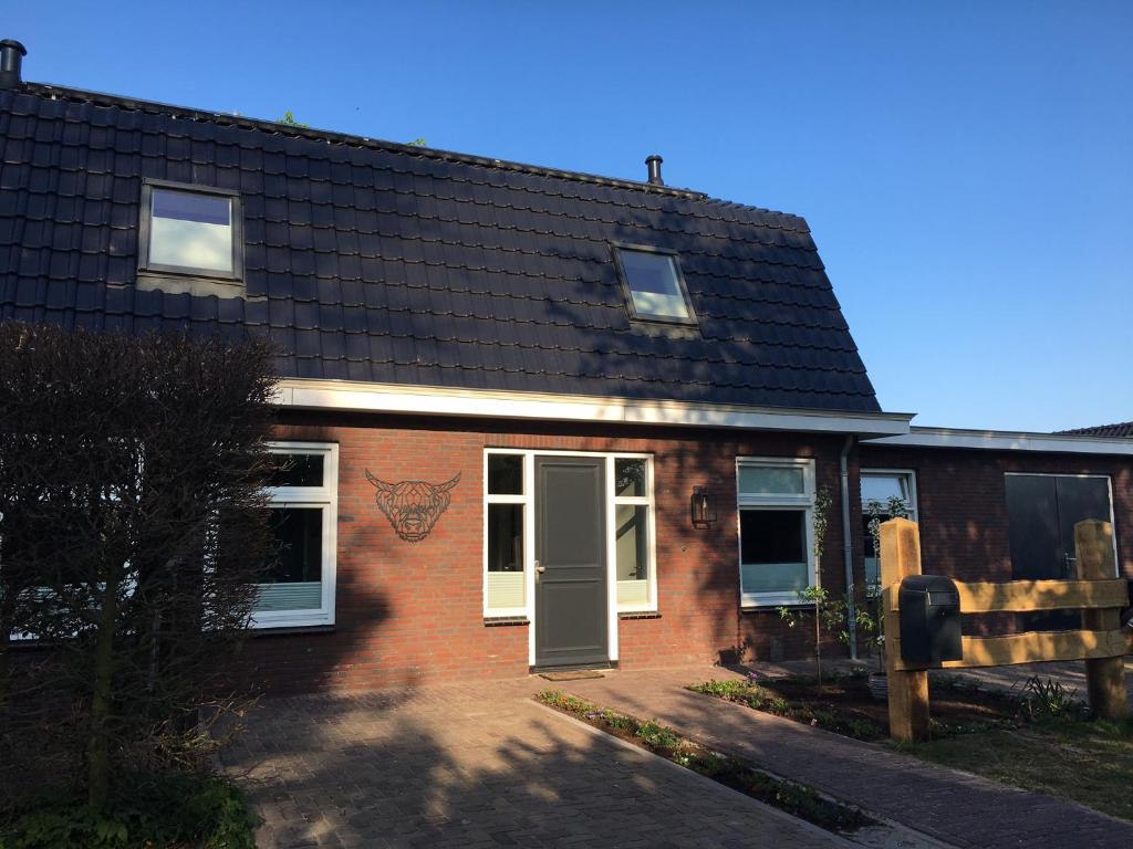 uma casa de tijolos com uma porta verde e uma cerca em Lowlander BnB em Heemskerk