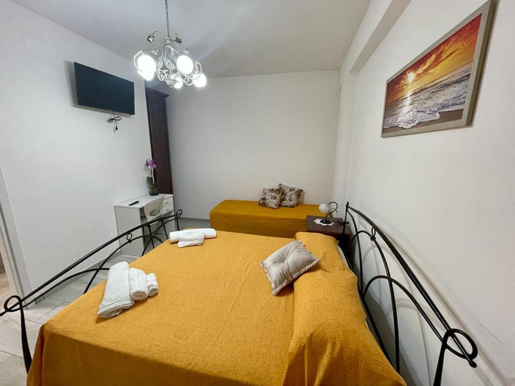 2 łóżka w pokoju z żółtą pościelą i ręcznikami w obiekcie Donnabella house w Agropoli