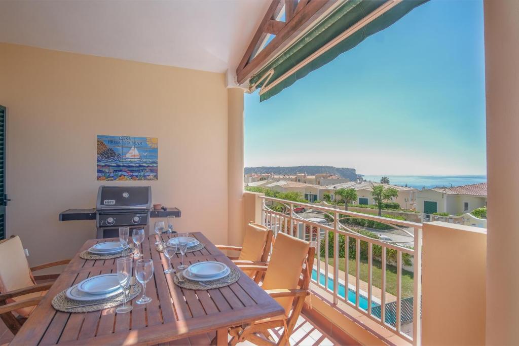 a wooden table with plates on top of a balcony at Villa Acacias 18, Brisa do Mar in Luz