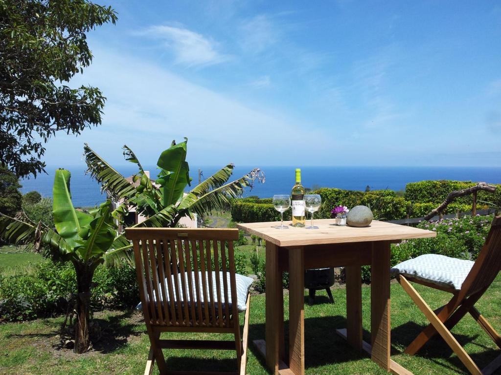 Faial Cottage B&B في Cedros: طاولة مع زجاجة من النبيذ وكرسيين