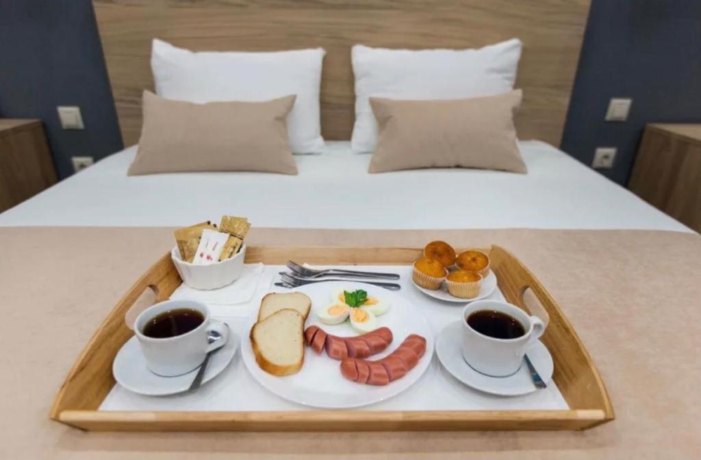 スフミにあるБутик-отель Белый Дом Балериныのベッドの上にコーヒー2杯と食料品のトレイ