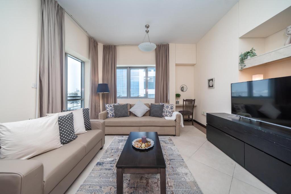 a living room with a couch and a tv at HiGuests - Deiras Lucky Find, 5-min to the Airport in Dubai