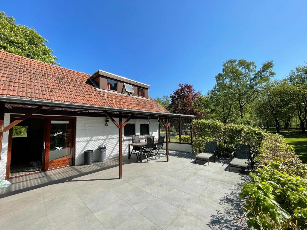 a patio with chairs and a table and a house at Cozy Holiday Home in Uden with huge private garden in Uden