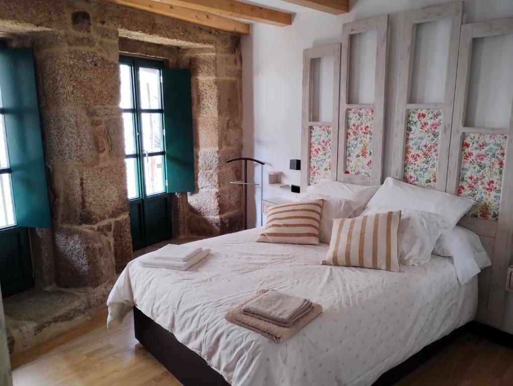 a bedroom with a large white bed with two pillows at Casiña da Madalena in Ribadavia