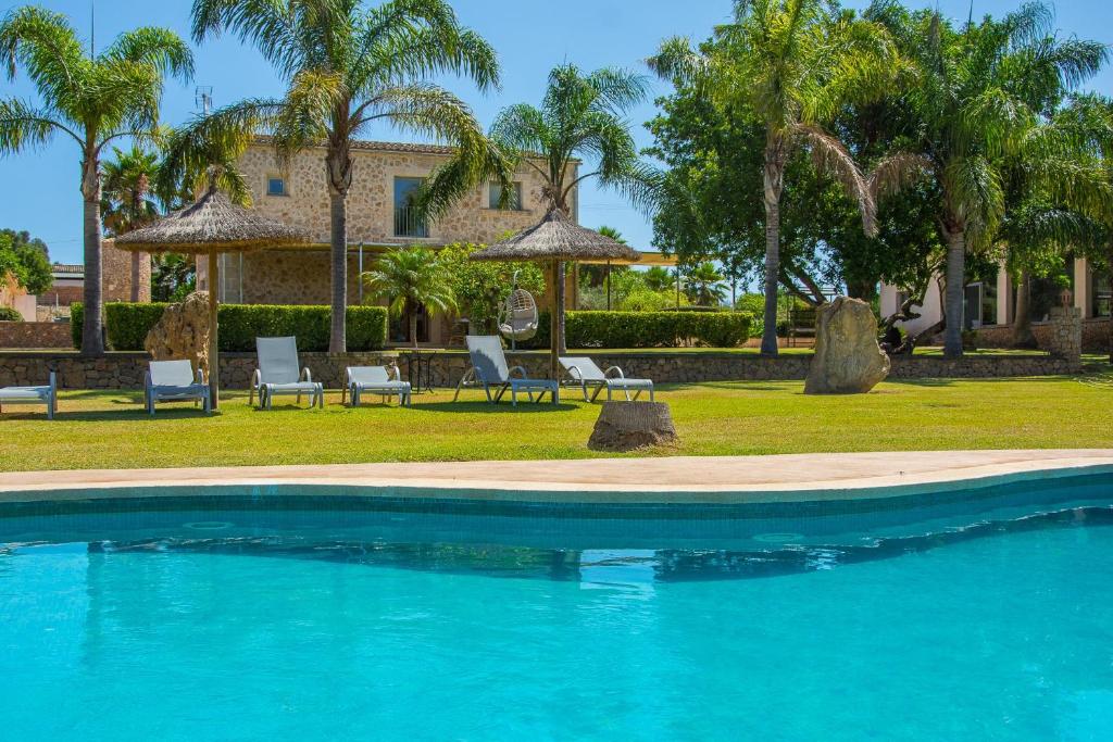 a swimming pool in front of a house with palm trees at Son Perot in Maria de la Salut