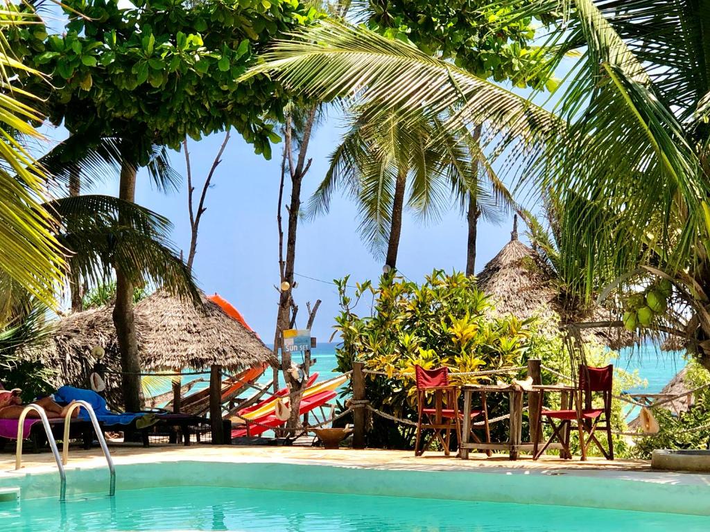 un complexe avec une piscine, une table et des chaises dans l'établissement Promised Land Lodge, à Kizimkazi