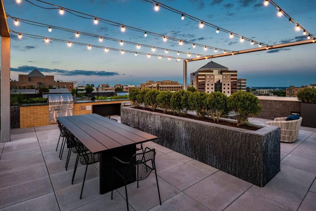 a table and chairs on a rooftop with lights at Gorgeous 1 Bedroom At Clarendon With Gym and Rooftop in Arlington