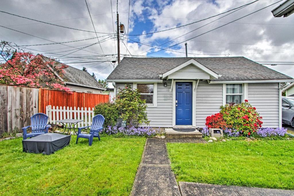 a house with a blue door and two chairs in the yard at Lovely Tacoma Cottage with Fire Pit, Near Dtwn! in Tacoma