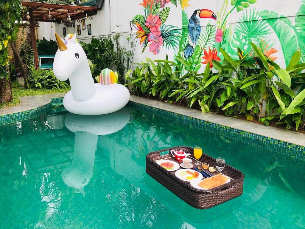 a pool with an inflatable unicorn and a tray of food at Double Mango Villa in Katunayaka