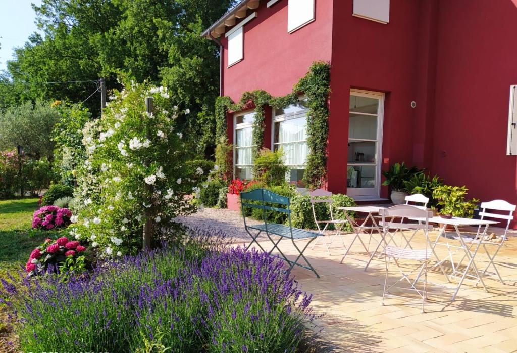 洛雷托阿普魯蒂諾的住宿－B&B Le Stagioni，一座红色的房子,前面有椅子和鲜花