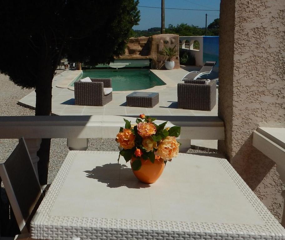 um vaso de flores sentado numa mesa ao lado de uma piscina em Chambre d'hôtes à Usclas d'Hérault em Usclas-lʼHérault