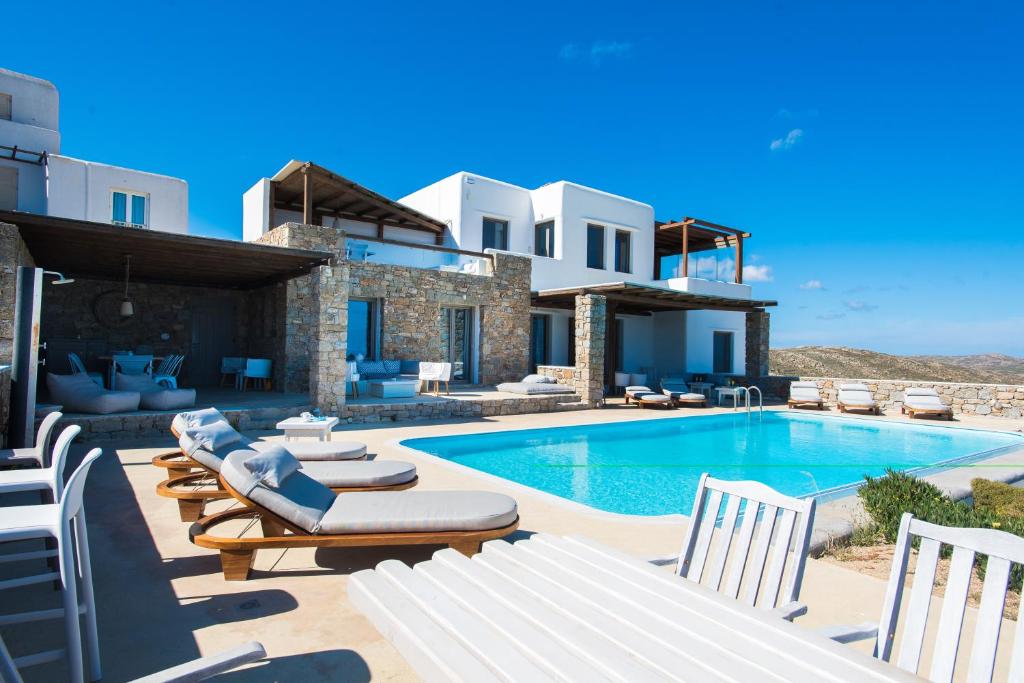 a villa with a swimming pool and lounge chairs at Amallini Suites Mykonos in Super Paradise Beach