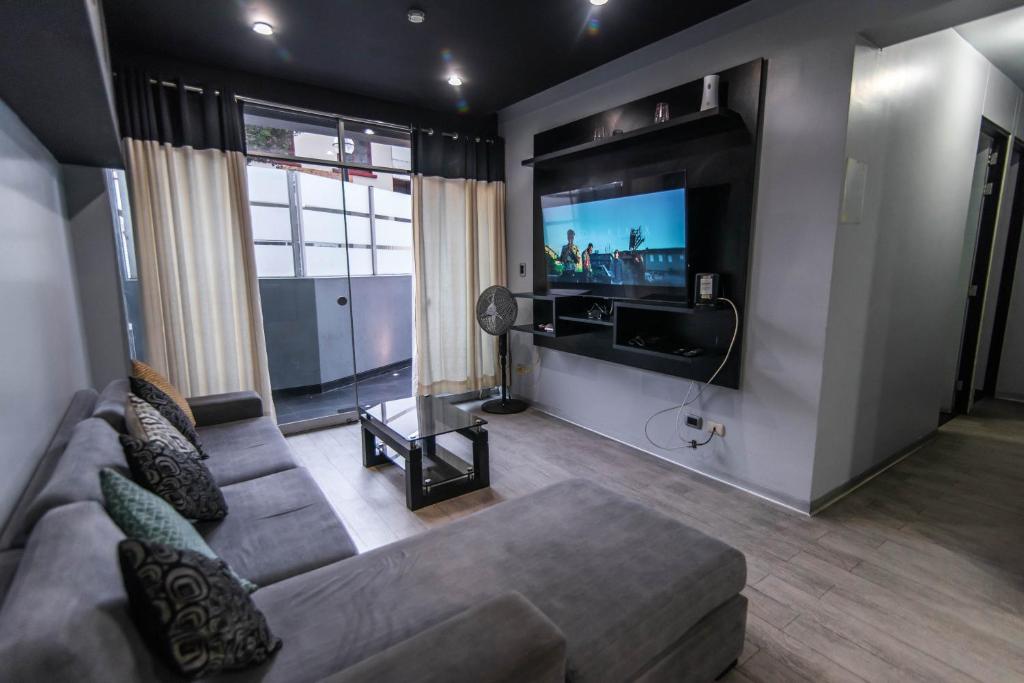 uma sala de estar com um sofá e uma televisão de ecrã plano em Miraflores Apartment em Lima