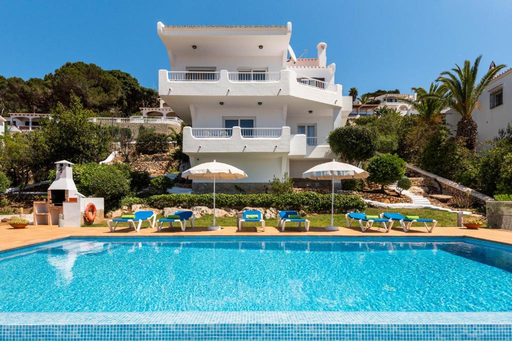 une villa avec une piscine en face d'un bâtiment dans l'établissement Villa Magdalena, à Alaior