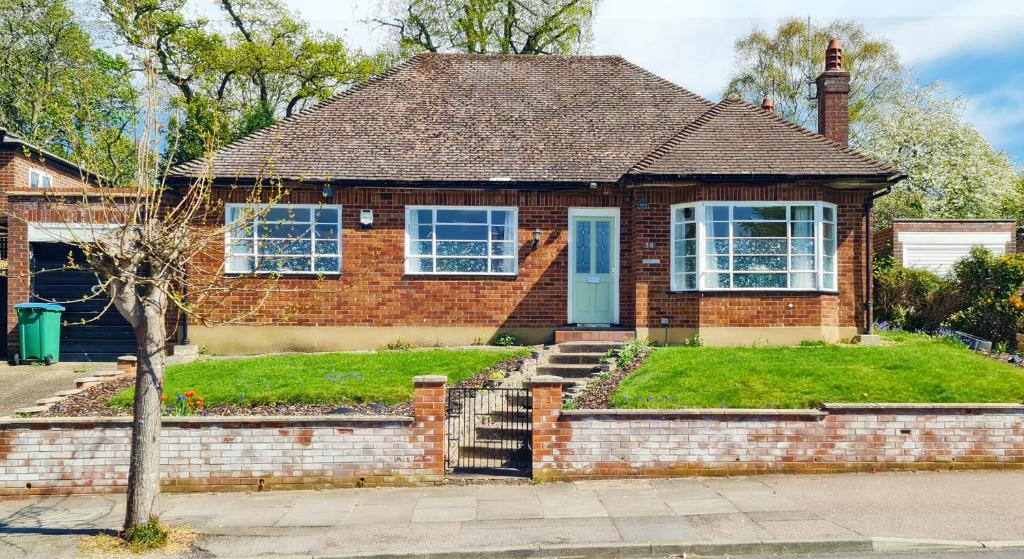 una casa de ladrillo con una puerta azul en Fairview Cottage Watford, en Leavesden Green