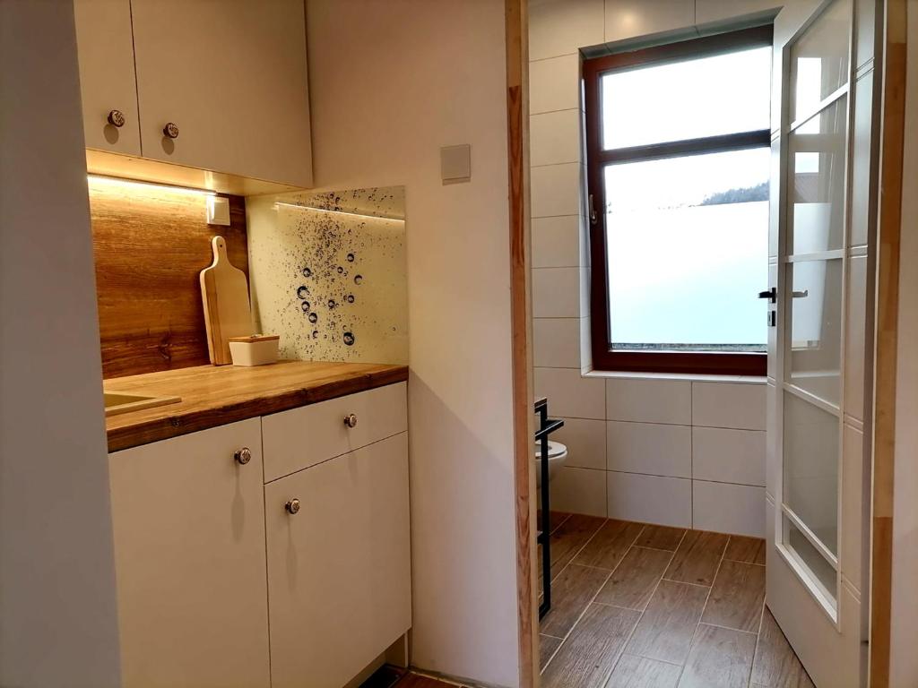 a small kitchen with white cabinets and a window at Willa pod Aniołem in Szczawnica