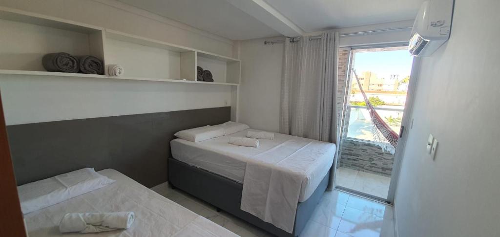 a small room with two beds and a window at Makambira Residence 201 in Porto De Galinhas