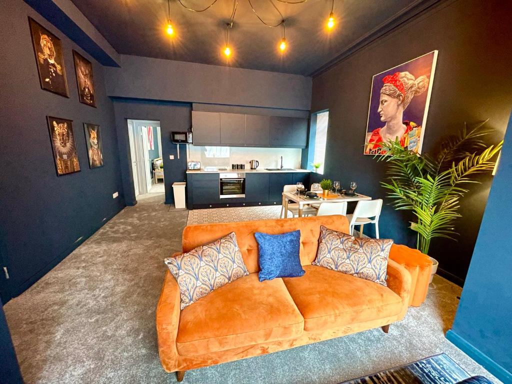 a living room with an orange couch and a kitchen at Stunning & Stylish 2 Bedroom Apartment! - 5 Minute Walk to the Best Beach! - Great Location - FREE Parking - Fast WiFi - Smart TV - Newly decorated - sleeps up to 4! Close to Bournemouth & Poole Town Centre & Sandbanks in Bournemouth