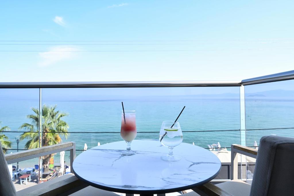 two glasses on a table with a view of the ocean at Emily's Luxury Suites in Pefkochori