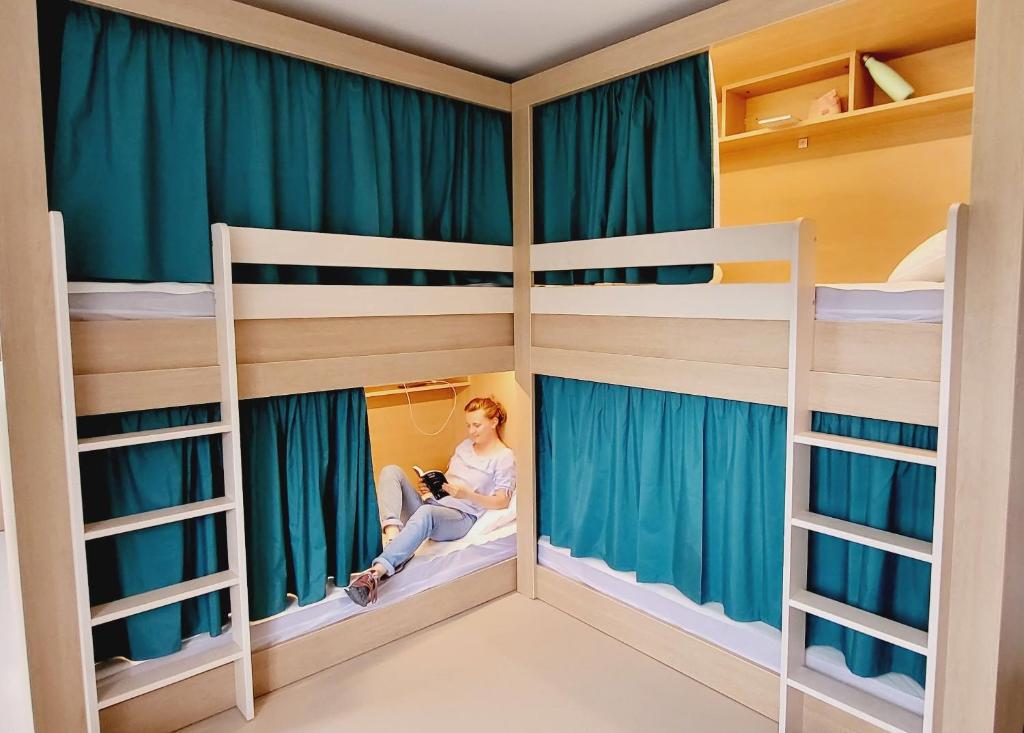 a woman sitting in a room with bunk beds at L'Etape du Mont, Family Hostel in Pontorson