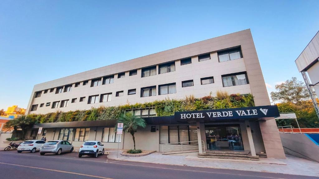 un bâtiment d'hôtel avec des voitures garées devant lui dans l'établissement Verde Vale Hotel, à Videira