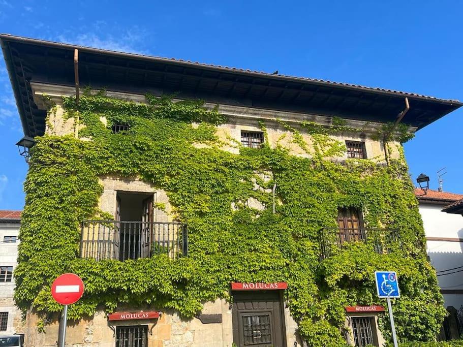 un bâtiment recouvert de lierre vert à côté d'un panneau d'arrêt dans l'établissement Apartamento Gaudi, à Comillas