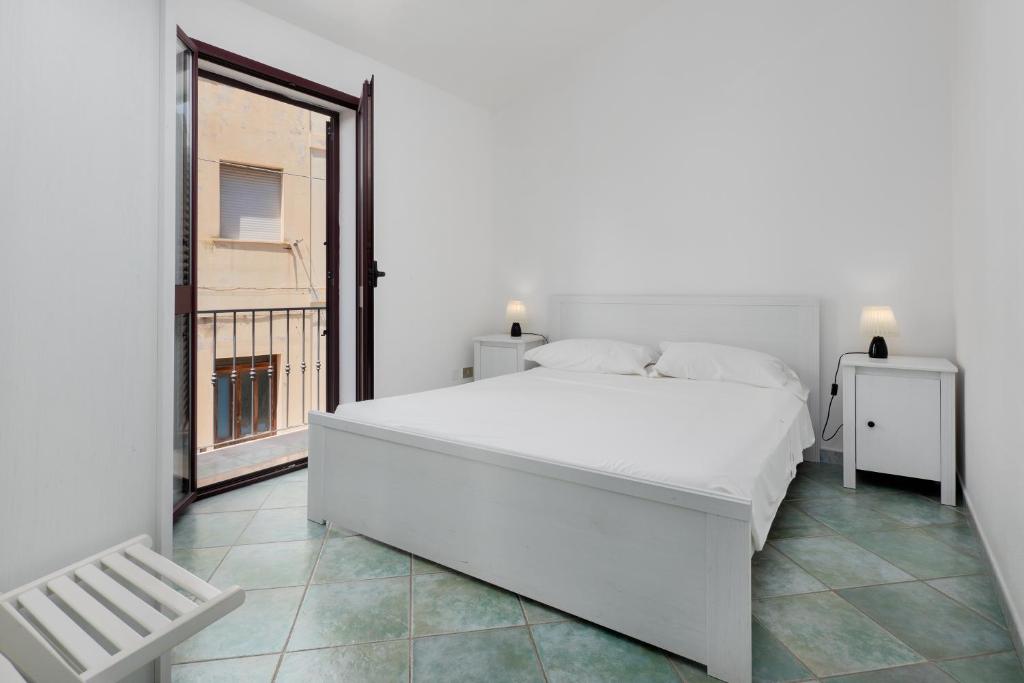 Un dormitorio blanco con una gran cama blanca y una ventana en APPARTAMENTO DEL CAPITANO, en Cala Gonone
