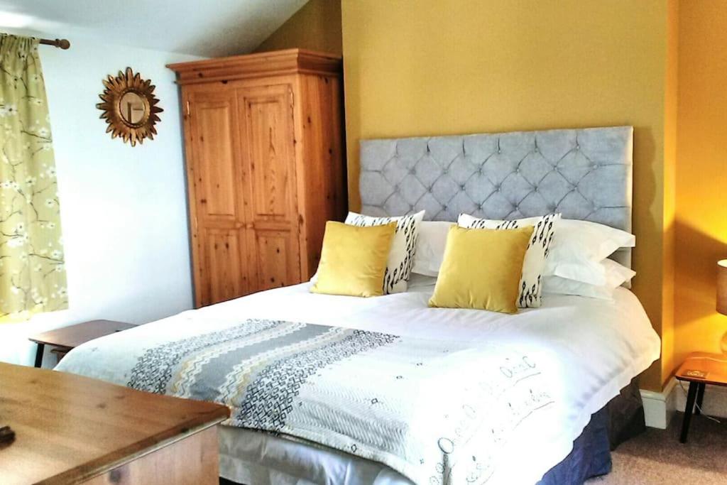 a bedroom with a large white bed with yellow walls at Wells Cottage in Malvern Wells