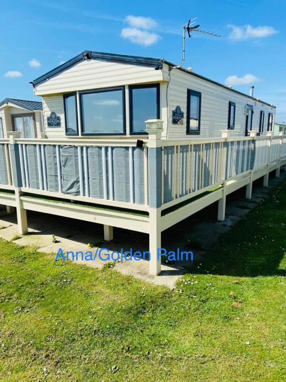 ein großes weißes Haus auf einem Steg im Gras in der Unterkunft Golden Palm, 8 Berth Caravan in Skegness