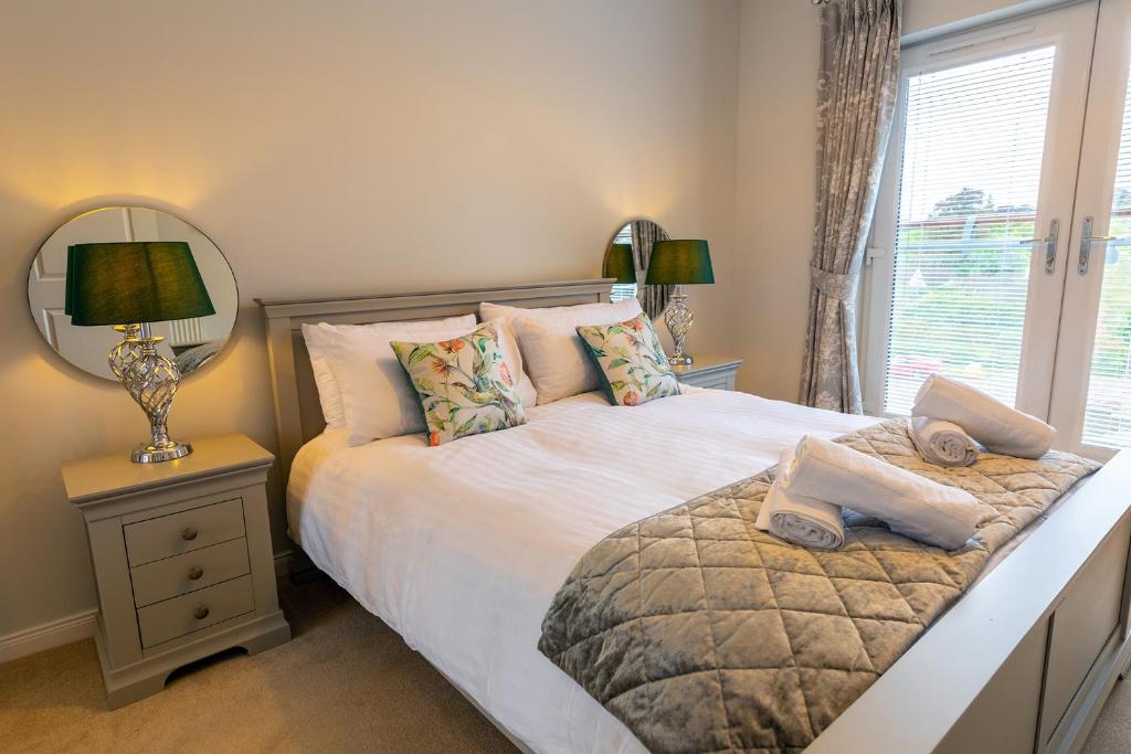a bedroom with a bed with a mirror and a window at Hedgefield House - Serene Top Floor Flat in Inverness