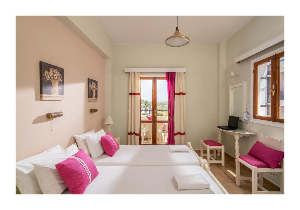 1 dormitorio con 1 cama blanca grande con almohadas rosas en Malia Semiramis by Estia en Malia
