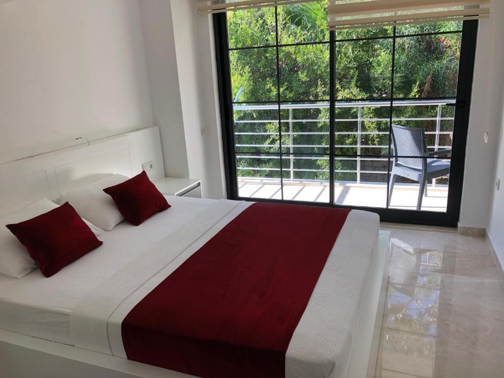 a bedroom with a bed with red pillows and a window at Stone House Aparts 2 plus 1 mit zwei Balkone und Poolview Kalkan No 10 in Kas
