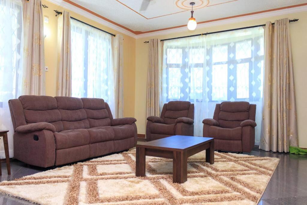 SERENE 4 BEDROOMED HOME IDEAL FOR FAMILY HOLIDAY في مومباسا: غرفة معيشة مع أريكة وكرسيين وطاولة