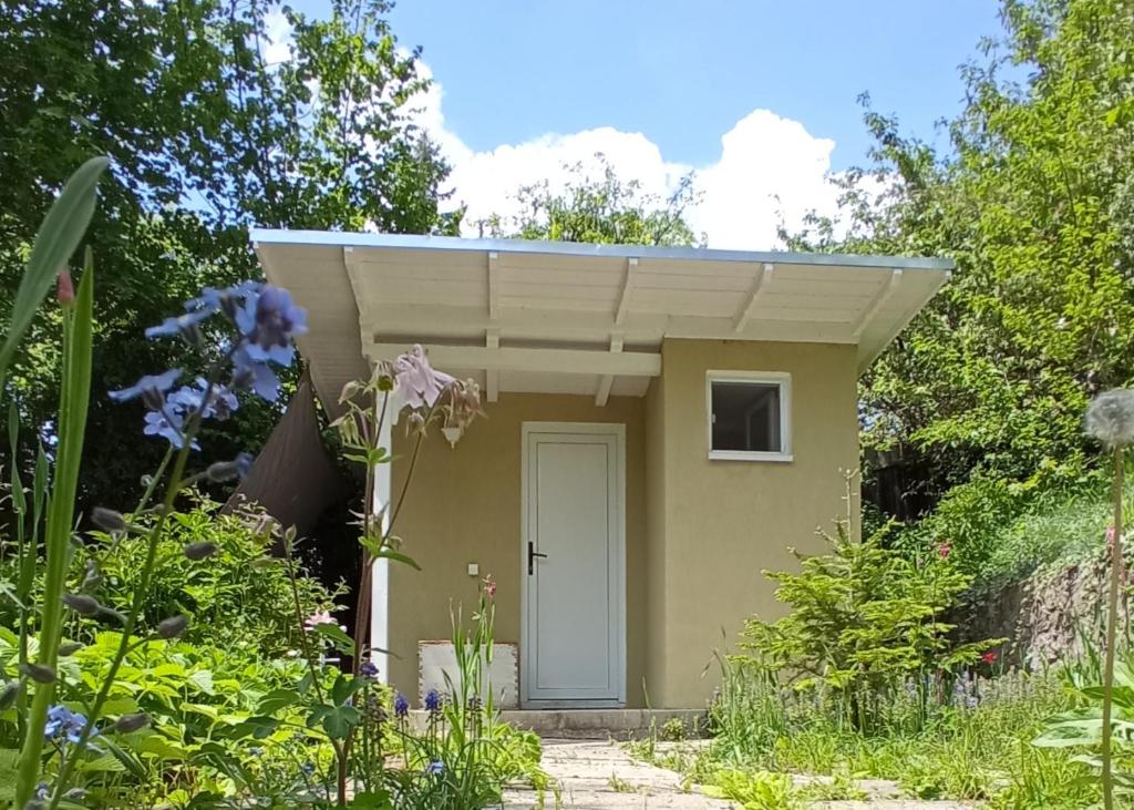 un pequeño cobertizo con una puerta blanca en un jardín en The Bungalow, en Brasov