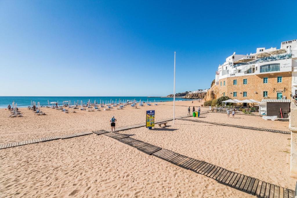 a sandy beach with chairs and people on the beach at Casa Mar Praia dos Pescadores By ALzira in Albufeira