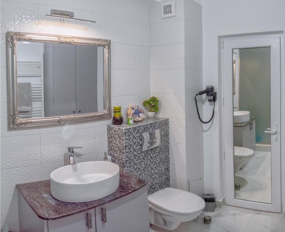 een badkamer met een wastafel, een toilet en een spiegel bij Duo Apartament in Năvodari